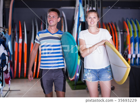 Young couple of surfers holding new surfboard Young couple of surfers holding new surfboard 35693229