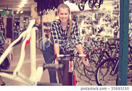 Portrait of woman who is standing with new bicycle indoors. Portrait of woman who is standing with new bicycle indoors. 35693230