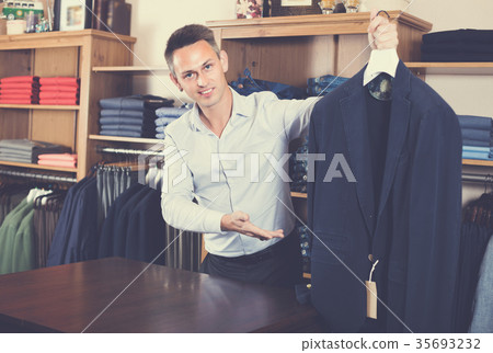 Young man is deciding on for new dark blue suit 35693232