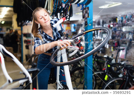Female is fixing wheels of bicycle in workshop. Female is fixing wheels of bicycle in workshop. 35693291