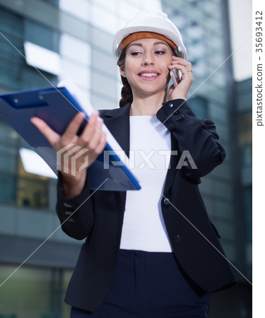 Woman architector in suit and hat is talking about project by the phone 35693412