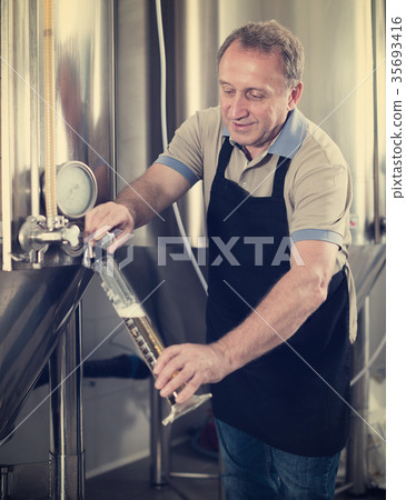 Brewer is controlling the quality of beer in flask Brewer is controlling the quality of beer in flask 35693416