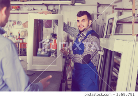 Production worker in coverall demonstrating different PVC windows to customer Production worker in coverall demonstrating different PVC windows to customer 35693791