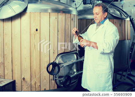 Adult brewer is standing with beer bottle Adult brewer is standing with beer bottle 35693909