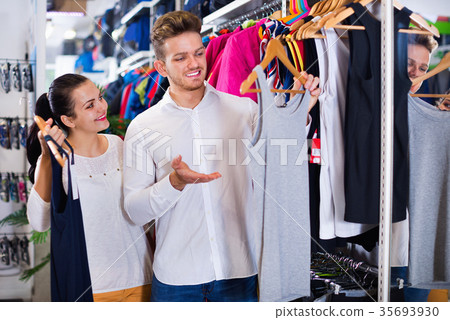 Couple examining various sports clothes in sports store Couple examining various sports clothes in sports store 35693930