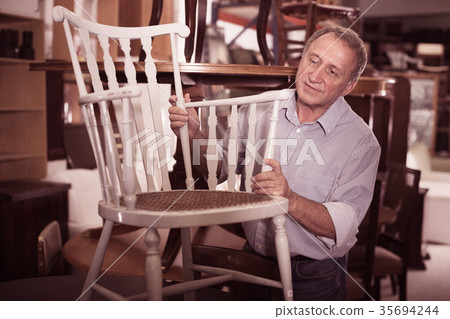 Mature male is choosing old chair for home Mature male is choosing old chair for home 35694244
