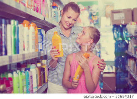 young mother with girl choosing bottles of sun protection indoors young mother with girl choosing bottles of sun protection indoors 35694317