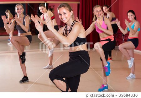 Young vigorous girls performing modern dance in fitness studio Young vigorous girls performing modern dance in fitness studio 35694330