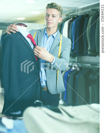 Seller in business clothes measuring jacket Seller in business clothes measuring jacket 35694331