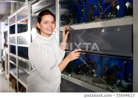 Girl looking at different breeds of small fish Girl looking at different breeds of small fish 35694615