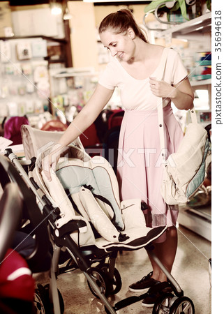 Happy pregnant woman buying baby stroller in kids mall Happy pregnant woman buying baby stroller in kids mall 35694618