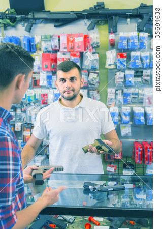 guy haelping customer to choose handgun in army market 35694638