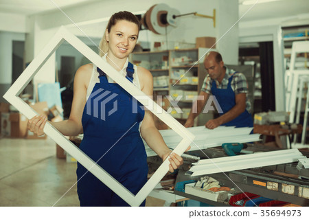 girl in workwear with window frame from pvc profile standing in girl in workwear with window frame from pvc profile standing in 35694973