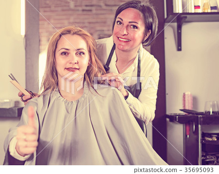 Young girl happy with her fashionable haircut and haircutter 35695093