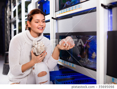 Girl at aquarium store choosing interesting stones, rocks and corals 35695098