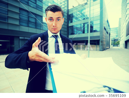 Office worker in suit is standing upset near office Office worker in suit is standing upset near office 35695109