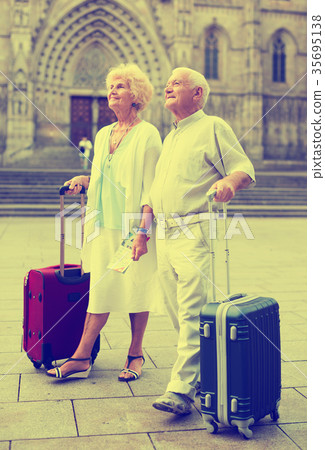 Mature travelers strolling with luggage 35695138