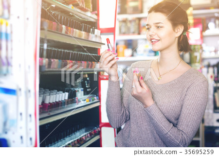 Smiling woman customer browsing rows of lipstick 35695259