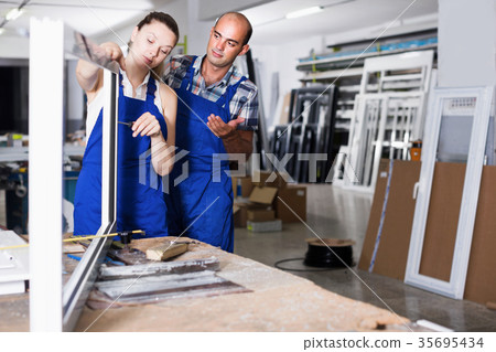 Two workers in blue overalls assembling pvc windows 35695434