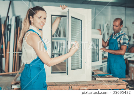 Workwoman in blue overalls demonstrating pvc window Workwoman in blue overalls demonstrating pvc window 35695482