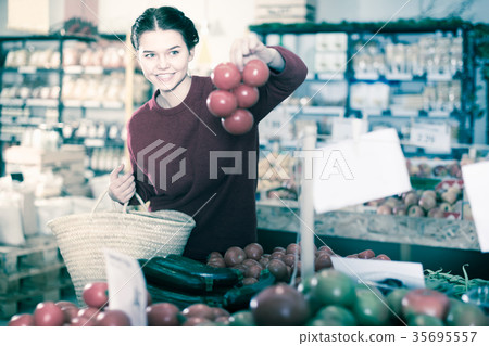 Young woman examines fresh tomatoes 35695557