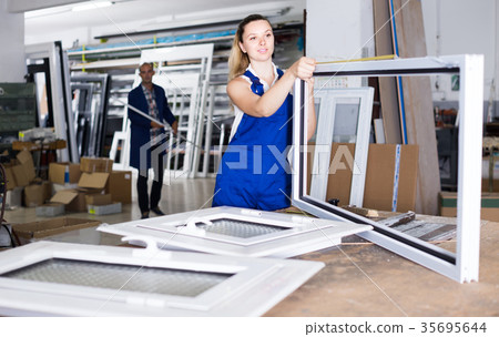 girl in workwear with window frame from pvc profile standing in workplace girl in workwear with window frame from pvc profile standing in workplace 35695644