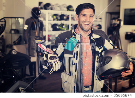 customer in jacket with helmet is choosing gloves 35695674