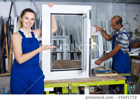 Portrait of female worker with finished plastic window in workshop Portrait of female worker with finished plastic window in workshop 35695719