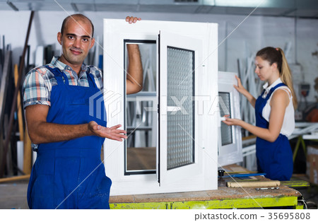 Portrait of male worker with finished plastic window in assembly shop Portrait of male worker with finished plastic window in assembly shop 35695808