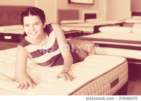 Young cheerful woman is lying on bed and testing mattress for relax Young cheerful woman is lying on bed and testing mattress for relax 35696070