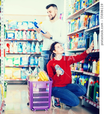 two vigorous adult people in good spirits selecting detergents in the store 35696119