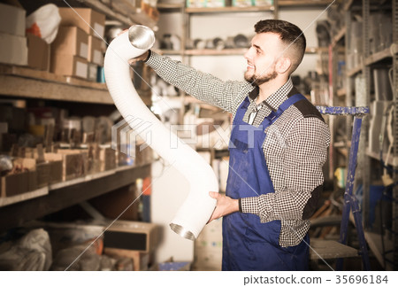 worker choosing flexible aluminum pipe for ventilation in workshop 35696184