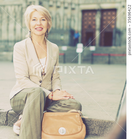 Cheerful mature female is walking sitting in classic jacket 35696422