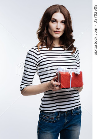 Charming woman holding red gift box with a bow 35702908