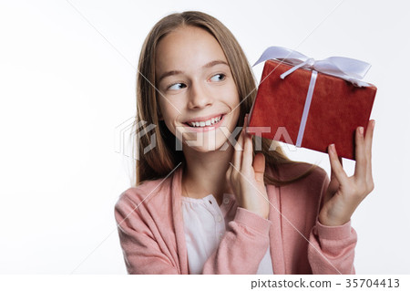 Adorable teenage girl looking at box with present 35704413