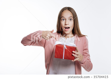 Charming teenage girl pointing at gift box with 35704415