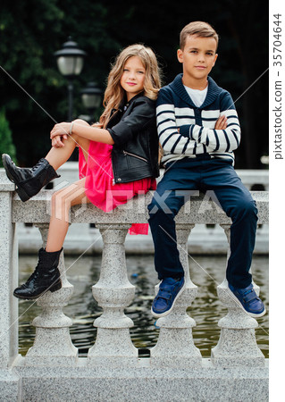 Two cute kids are sitting on the railing. Marble 35704644