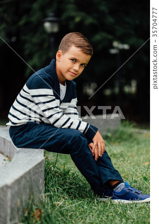 Young boy sitting on curb 35704777