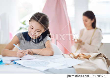 Delighted cute girl writing in her notebook 35704782