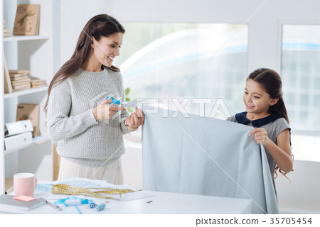 Pleasant young woman cutting a piece of cloth 35705454