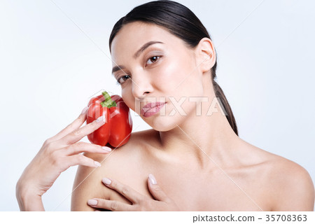 Charming brunette holding bell pepper on shoulder Charming brunette holding bell pepper on shoulder 35708363