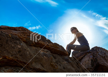 Woman sitting on a peak of a cliff 35711131