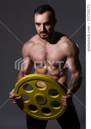Young muscular man with a disc in the studio Young muscular man with a disc in the studio 35720271