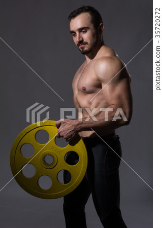 Muscular bodybuilder guy doing exercises with dumbbell Muscular bodybuilder guy doing exercises with dumbbell 35720272
