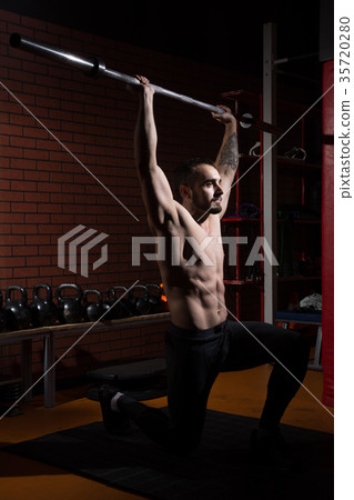 Young muscular man with a barbell bar in gym Young muscular man with a barbell bar in gym 35720280
