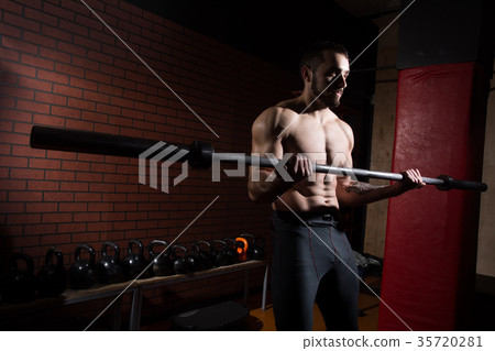 Young muscular man with a barbell bar in gym 35720281