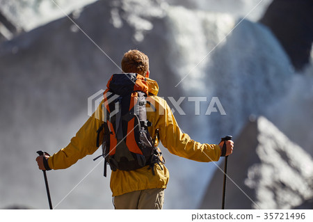 Hiker hiking with backpack looking at waterfall Hiker hiking with backpack looking at waterfall 35721496