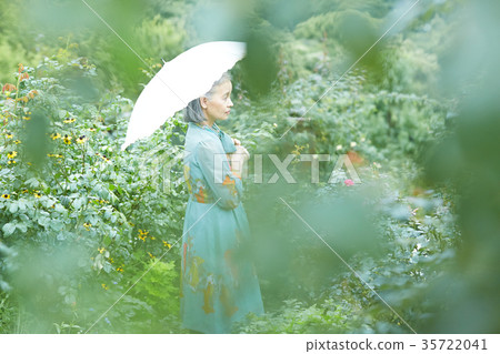 Senior woman holding a parasol in the garden Senior woman holding a parasol in the garden 35722041