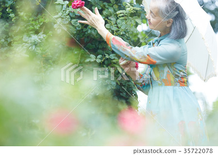 Senior woman holding a parasol in the garden 35722078