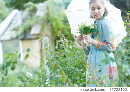 Senior Woman Holding A Parasol In The Garden Stock Photo